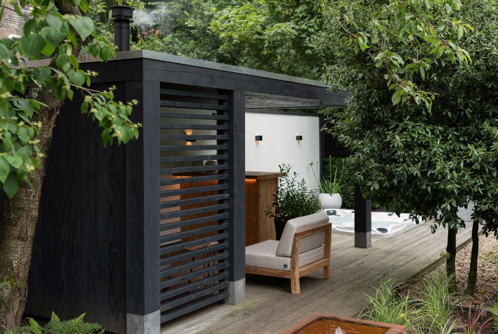 Tuinkamer van hout met zwarte lamellen en een vlonder met verzonken jacuzzi